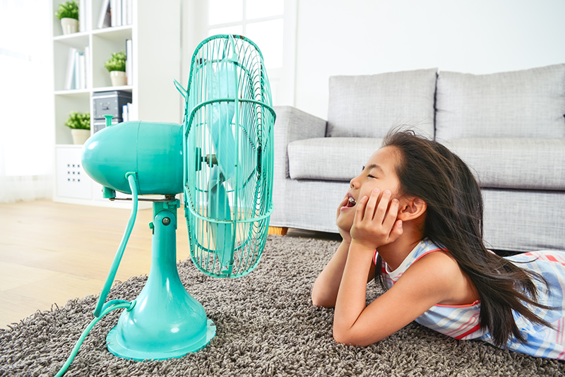 Little girl staying cool with a fan
