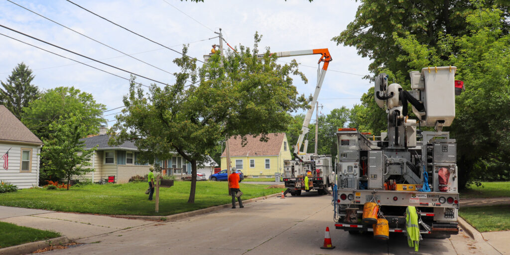 We Energies lineworkers work to make repairs to electric equipment in a residential area.